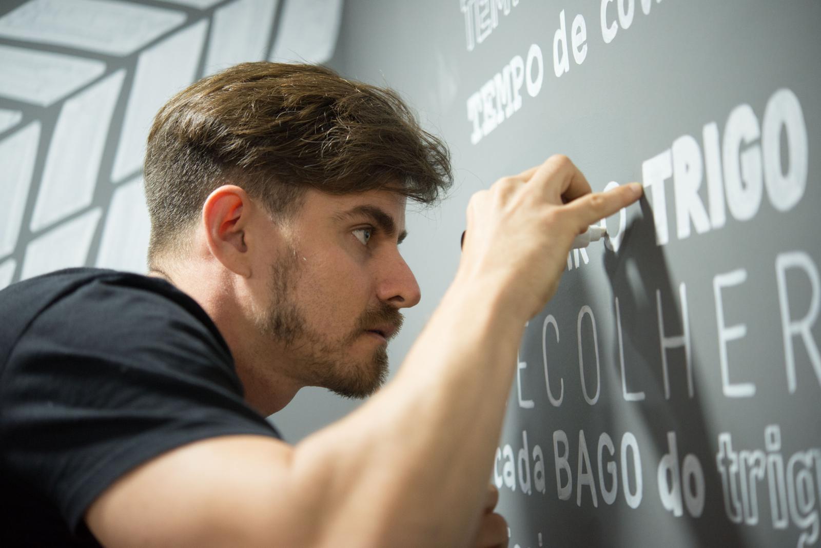 Editorial portrait — Richard writing on a wall about wheat, Salvador